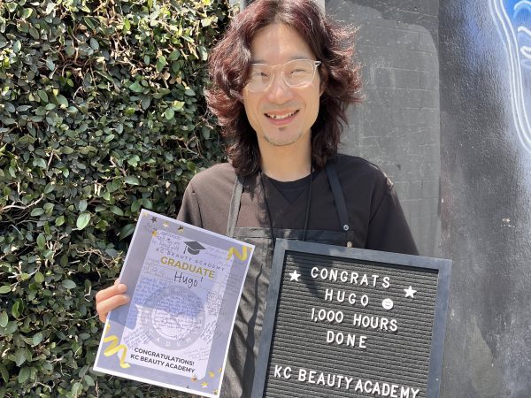 KC Beauty Academy graduate holding a milestone sign