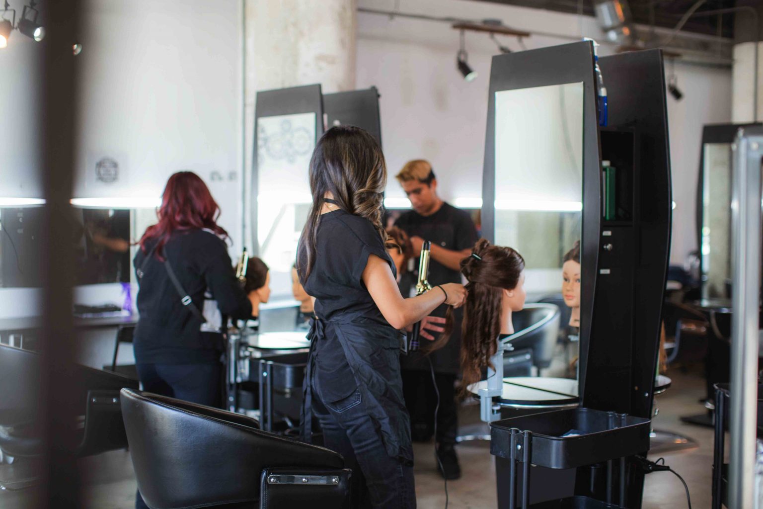 Cosmetology students practicing hair styling on the KC Beauty Academy salon floor